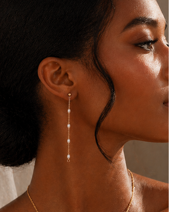 Close-up of a woman wearing pearl drop earrings with a neutral background