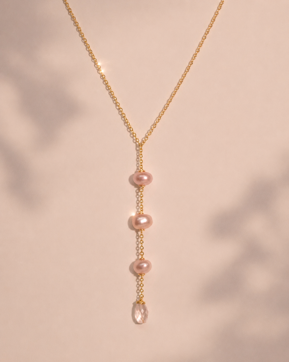 Gold necklace with pink pearls on a soft pink background