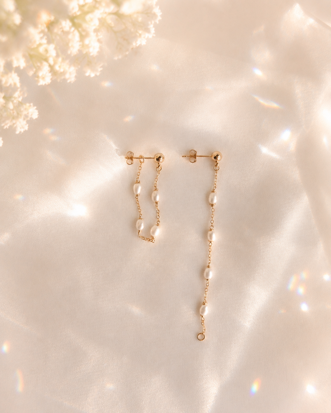 Gold earrings with pearl-like beads on a soft, blurred background