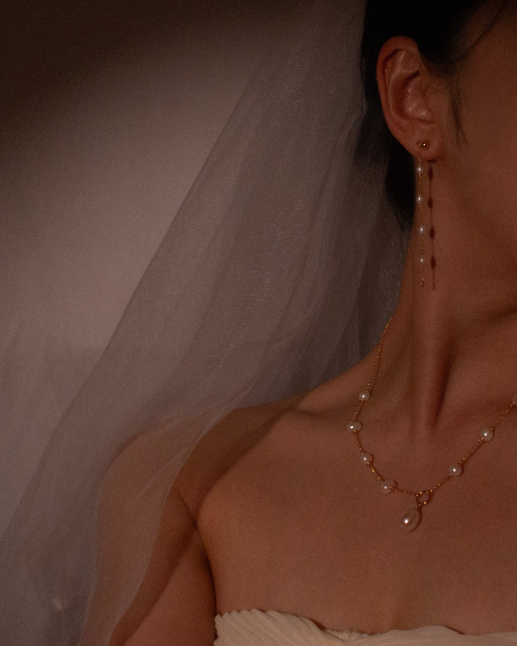 Pearl necklace and earrings on a person with a soft, neutral background