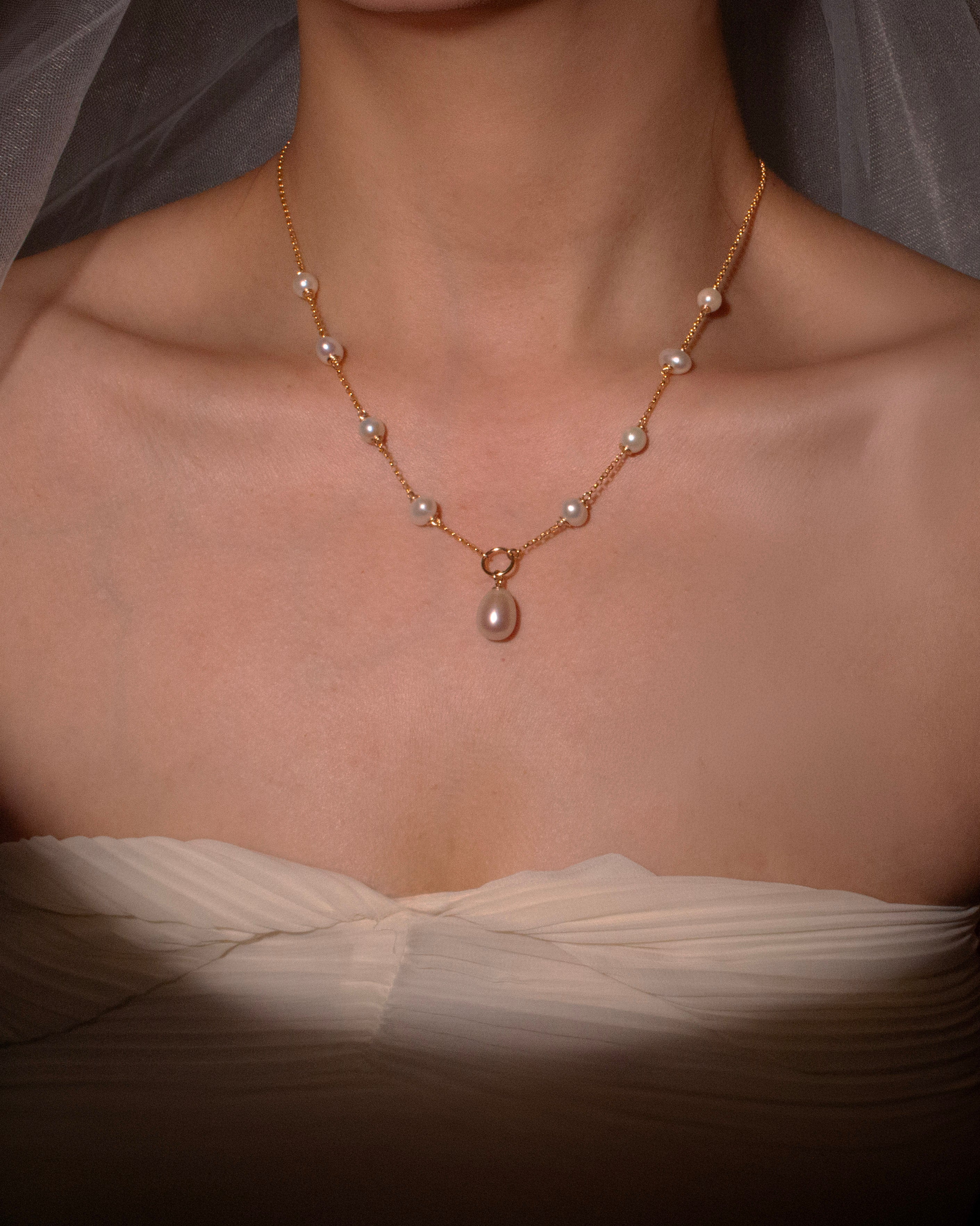 Pearl necklace on a person wearing a white dress with a soft focus background