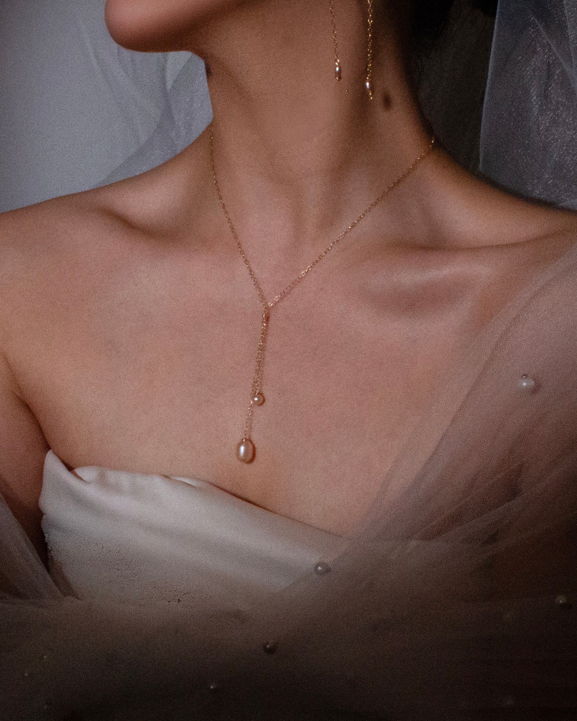 Close-up of a pearl necklace on a person wearing a white top.