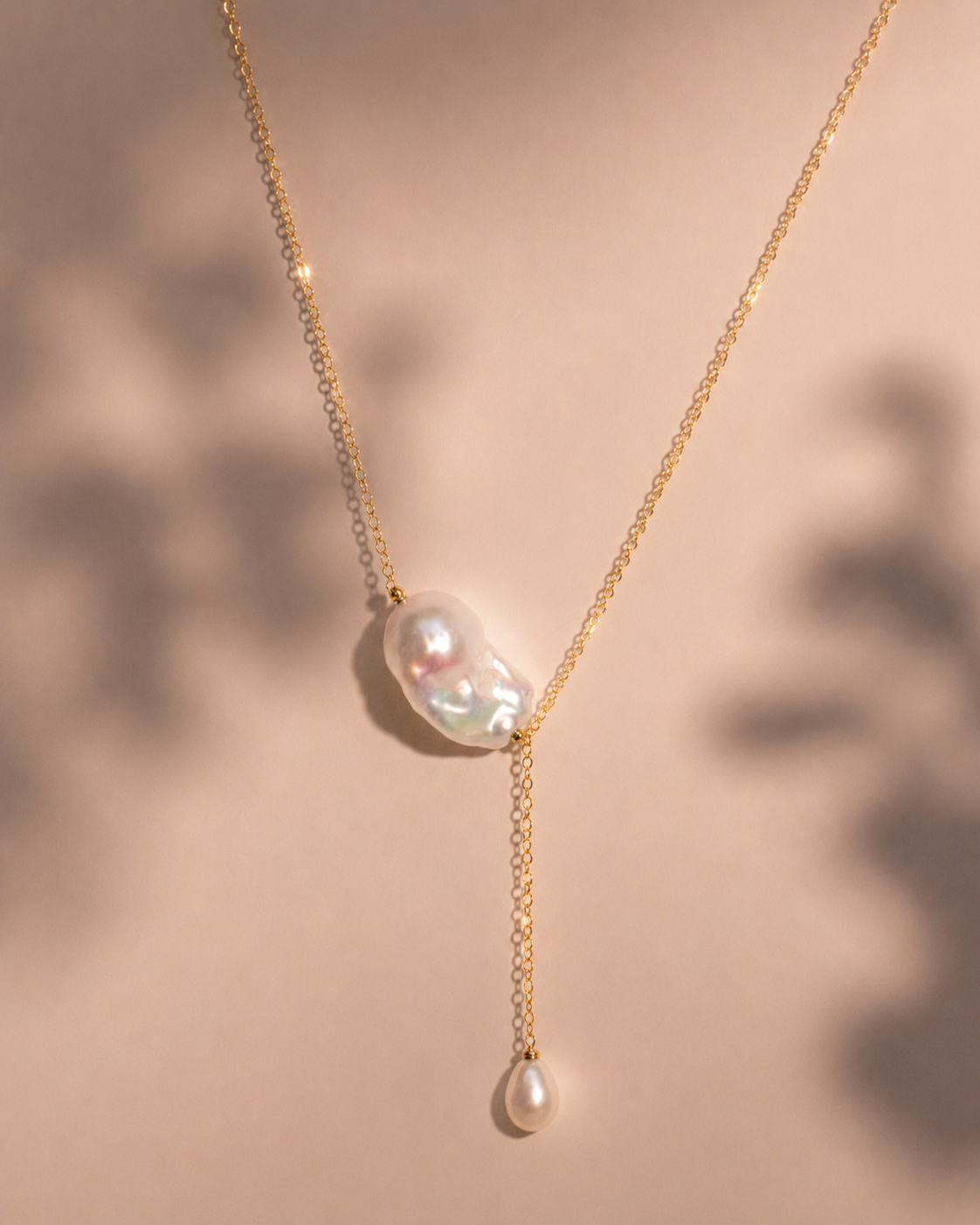 Gold necklace with pearl pendant on a beige background
