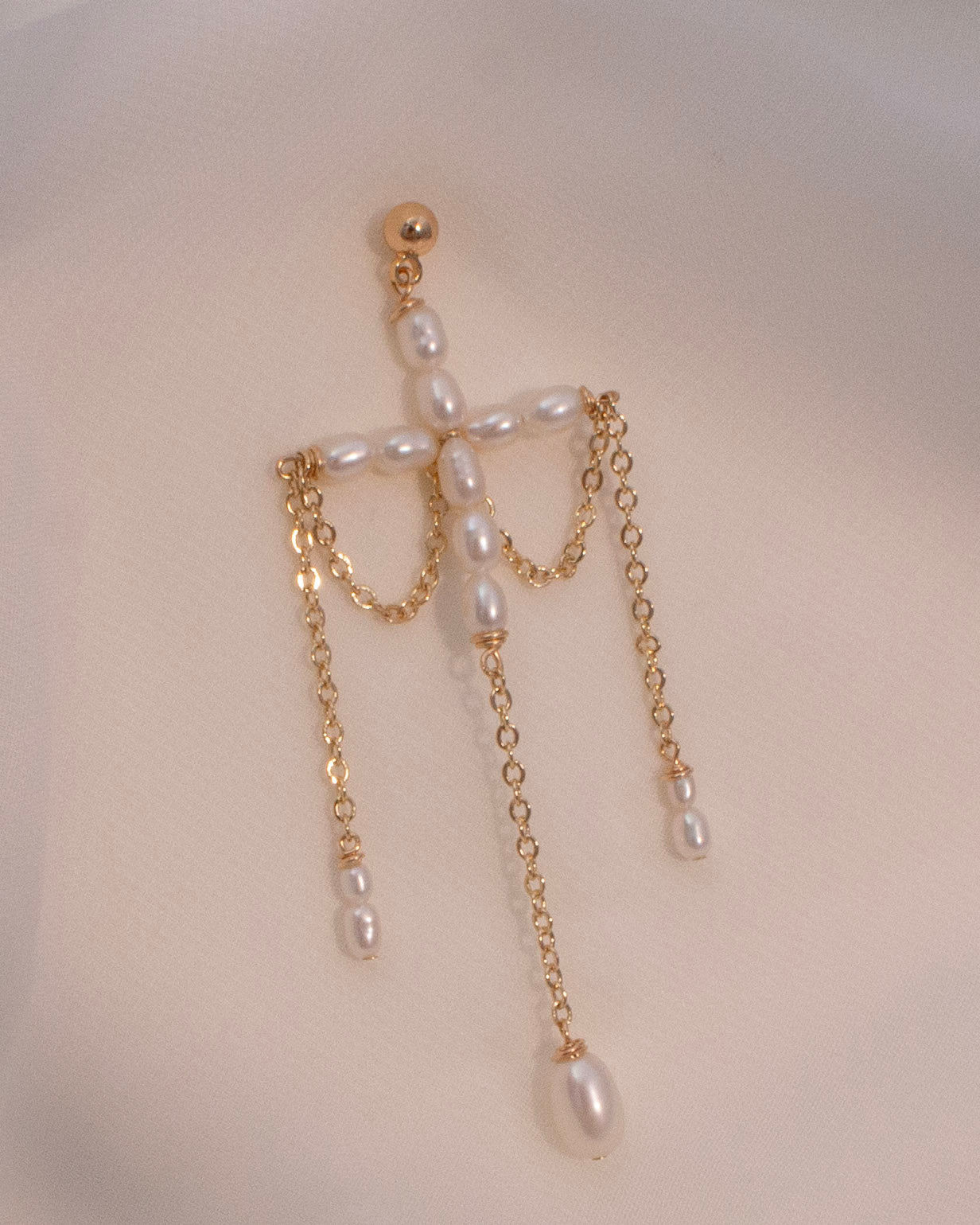 Pearl and gold chain earring on a mannequin head.