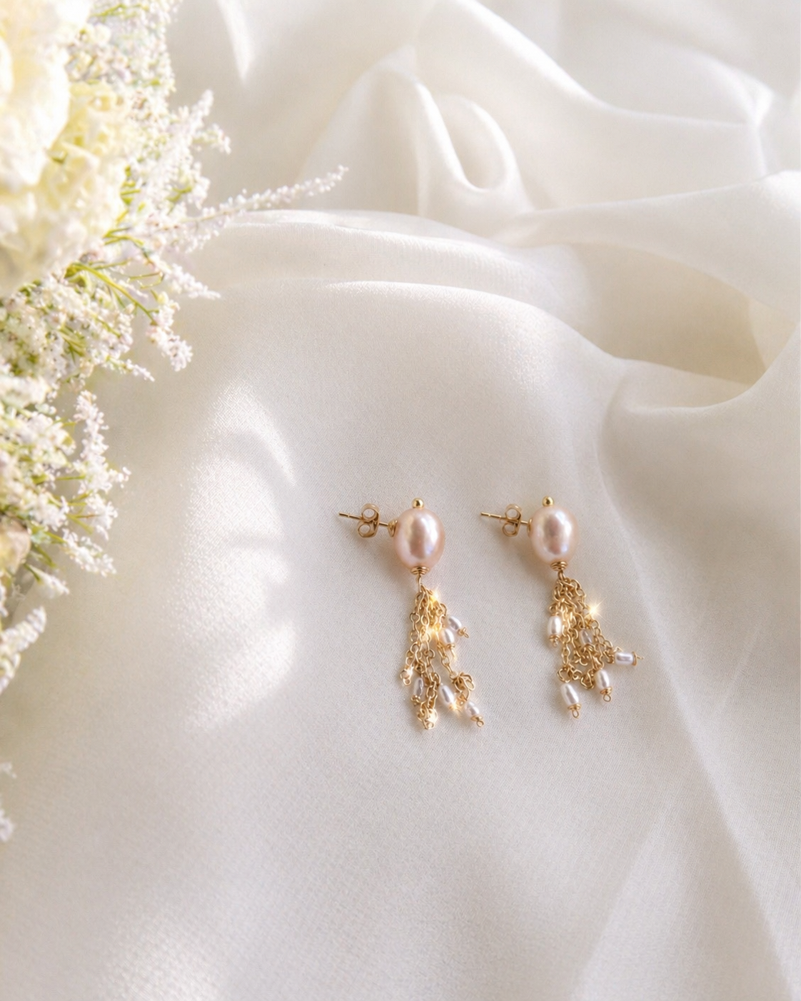 Gold earrings with pearls on a white fabric background