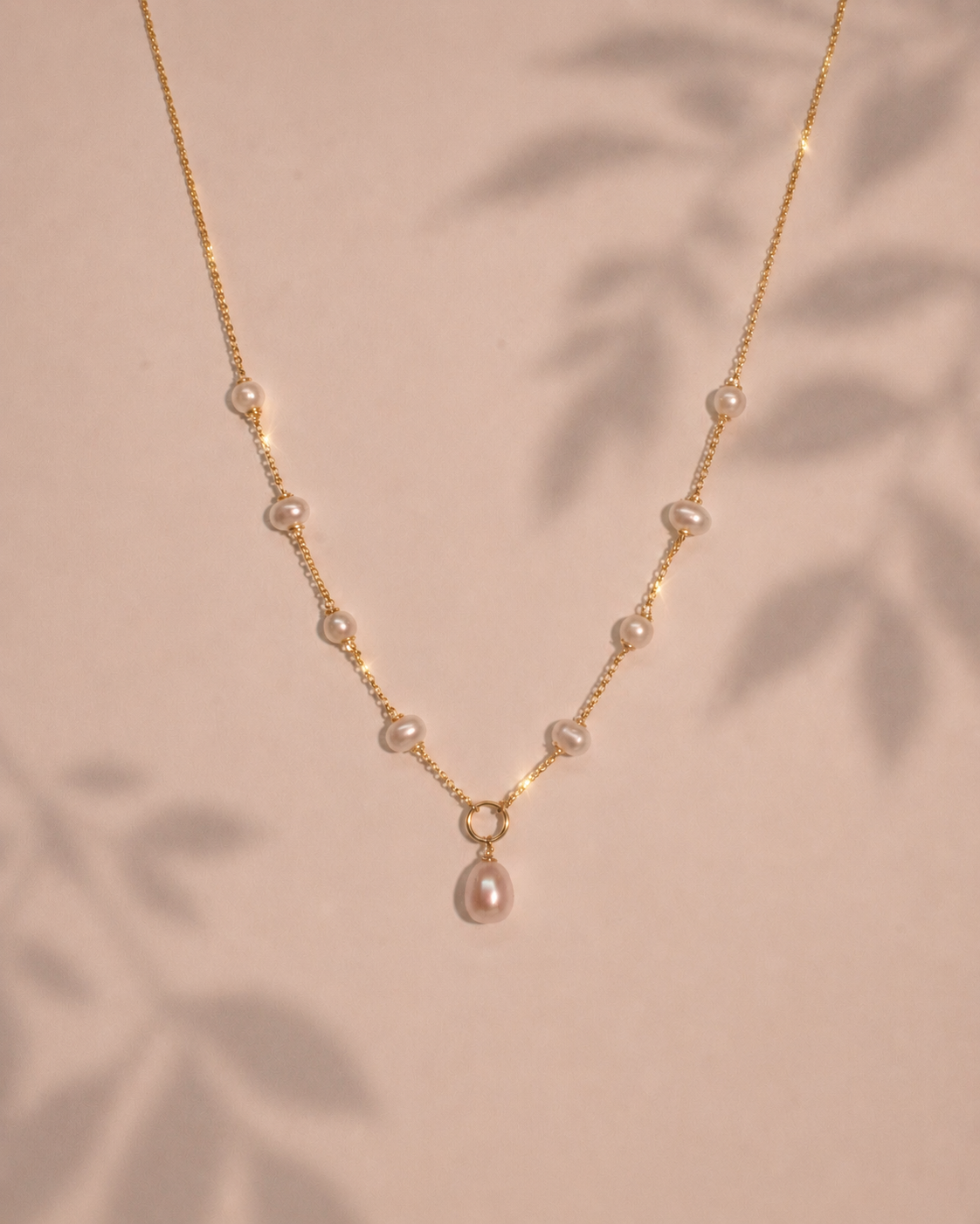 Pearl necklace with gold chain on a beige background