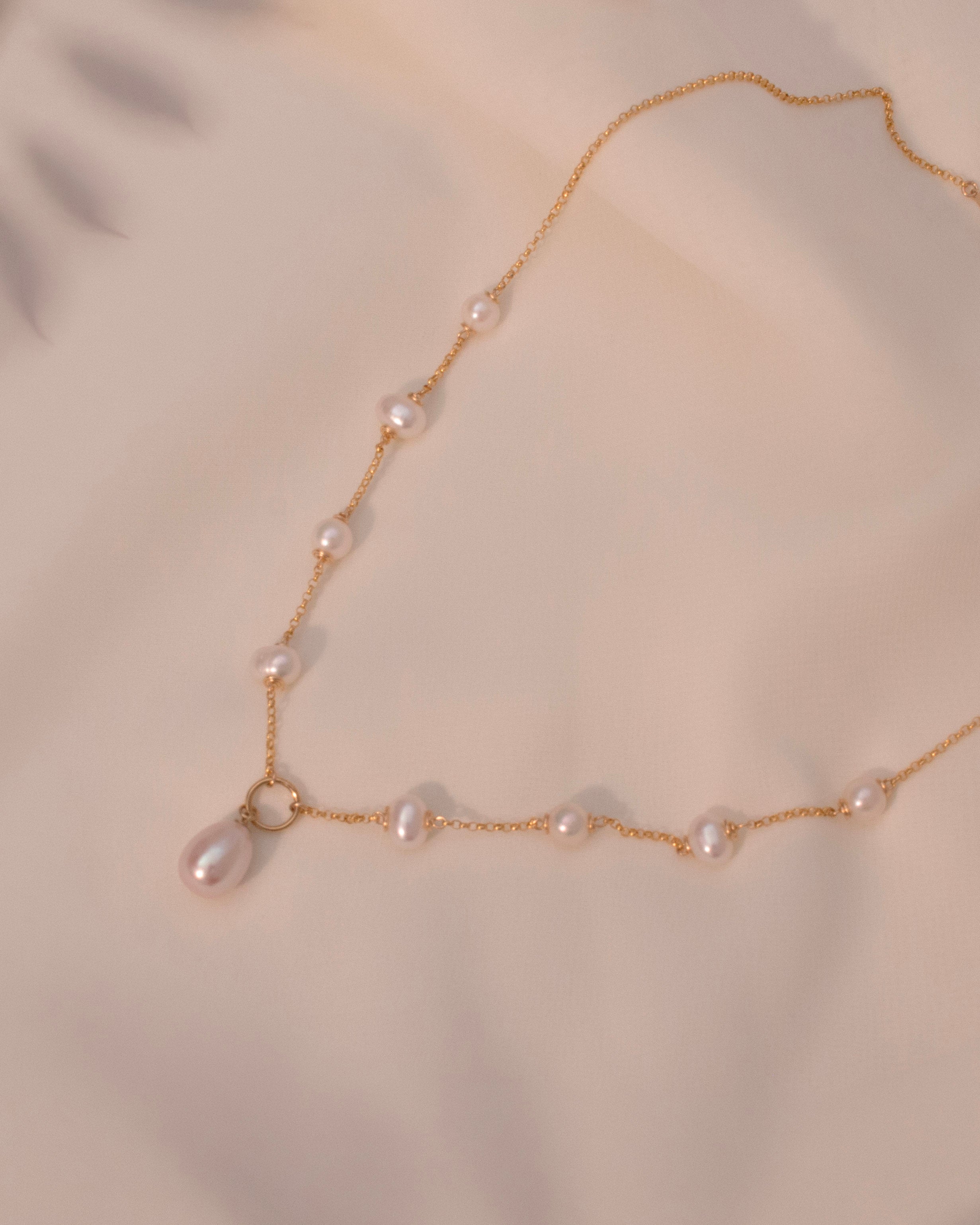 Gold necklace with pearls on a beige background