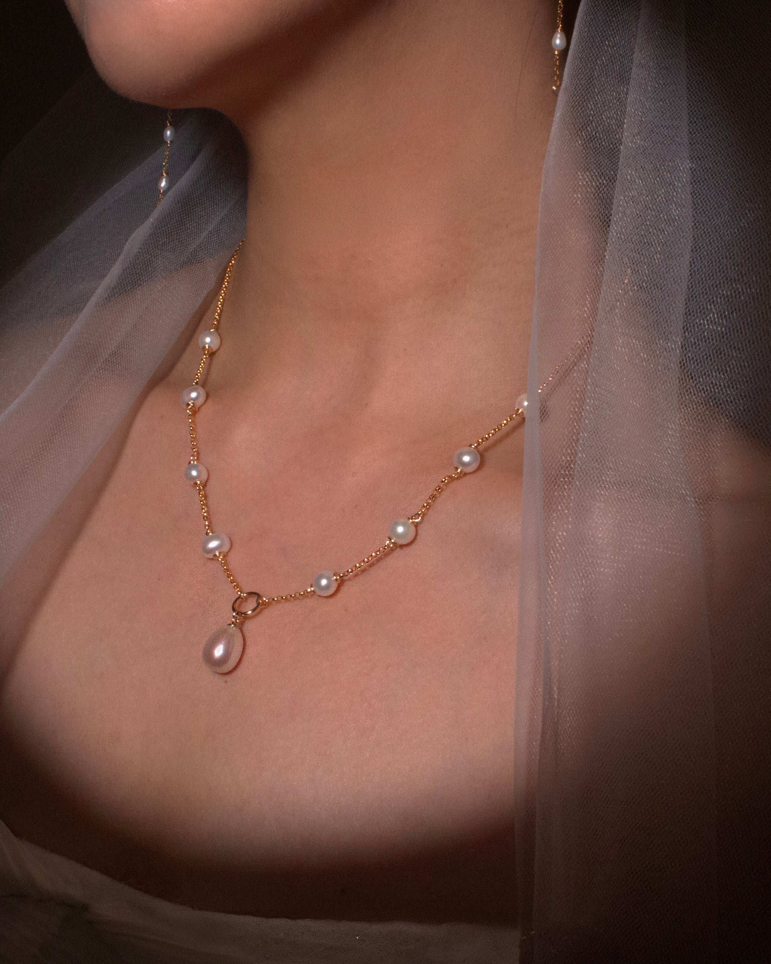 Pearl necklace worn by a person with a soft focus background