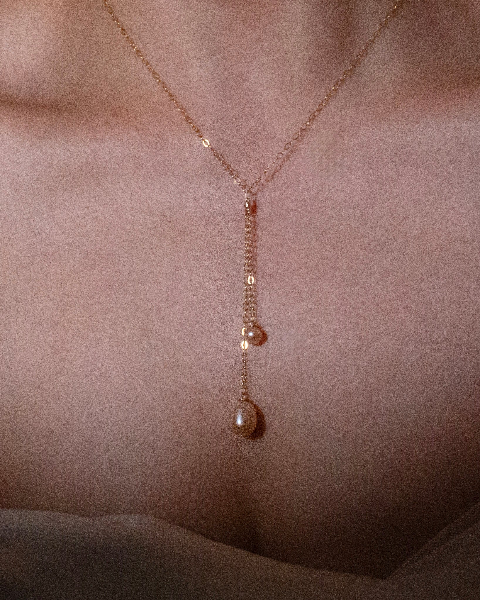 Delicate necklace with a pearl pendant on a person's neck