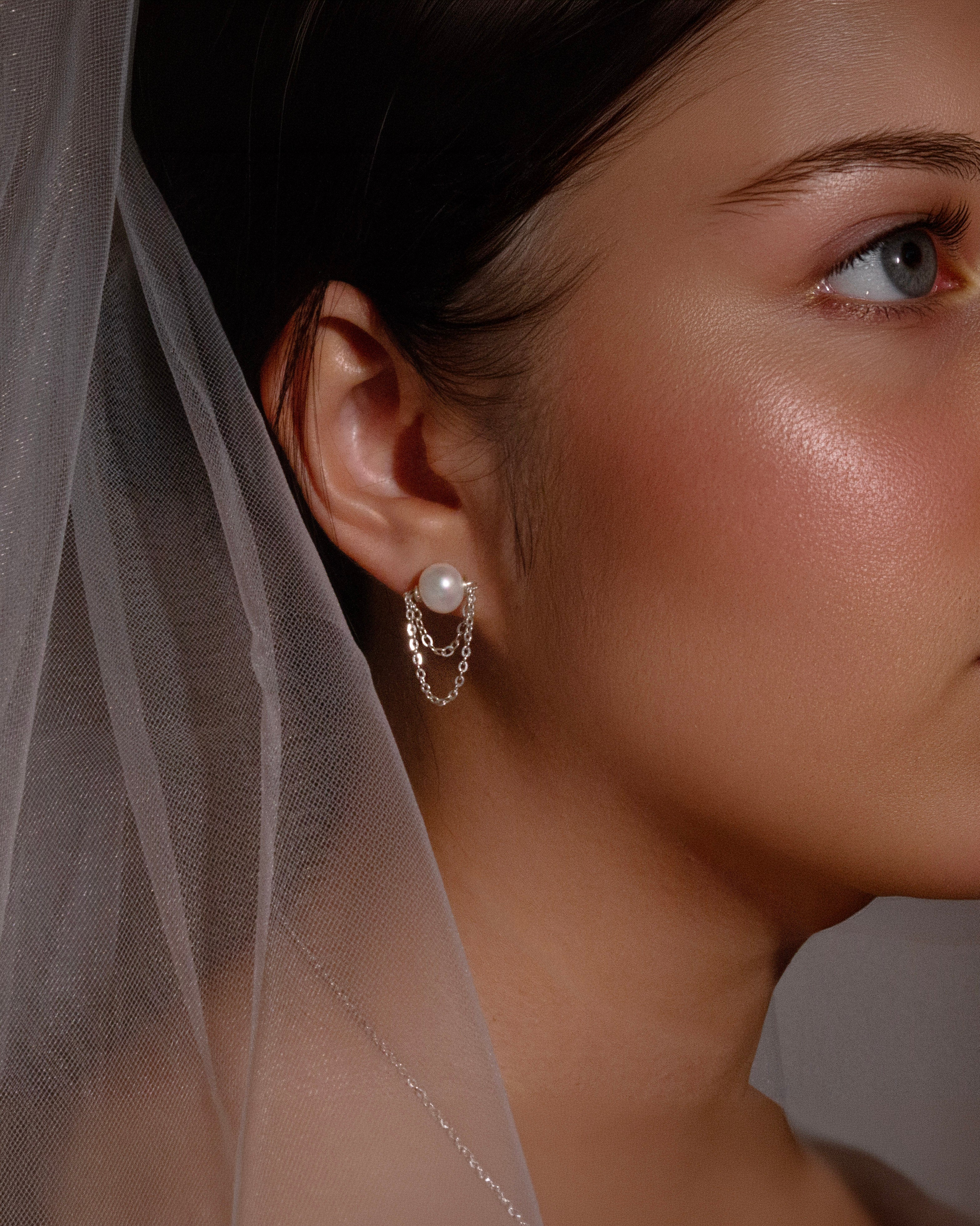 Close-up of a woman wearing pearl earrings with a soft focus background