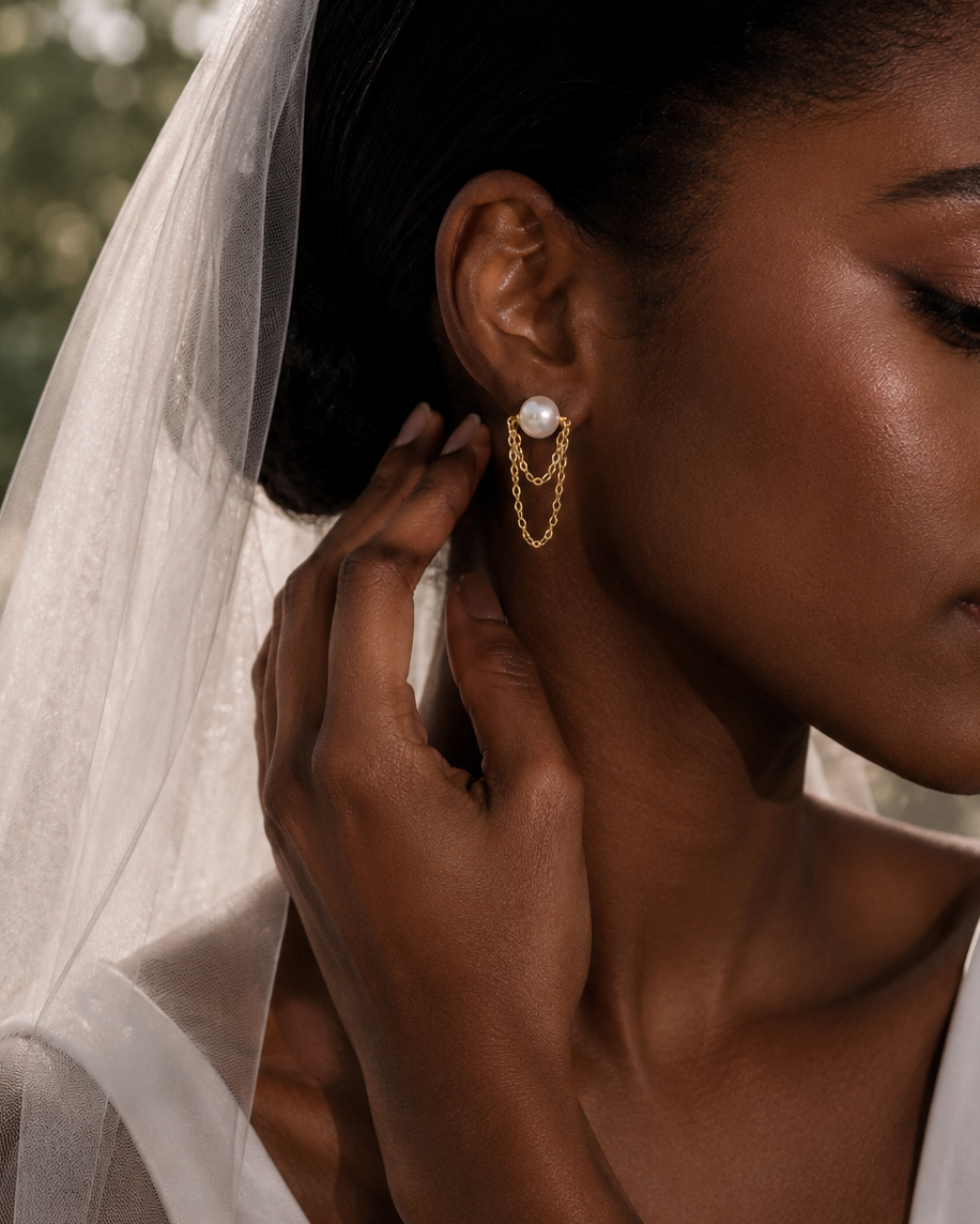 Woman wearing gold earrings with a veil, close-up of face and hand.
