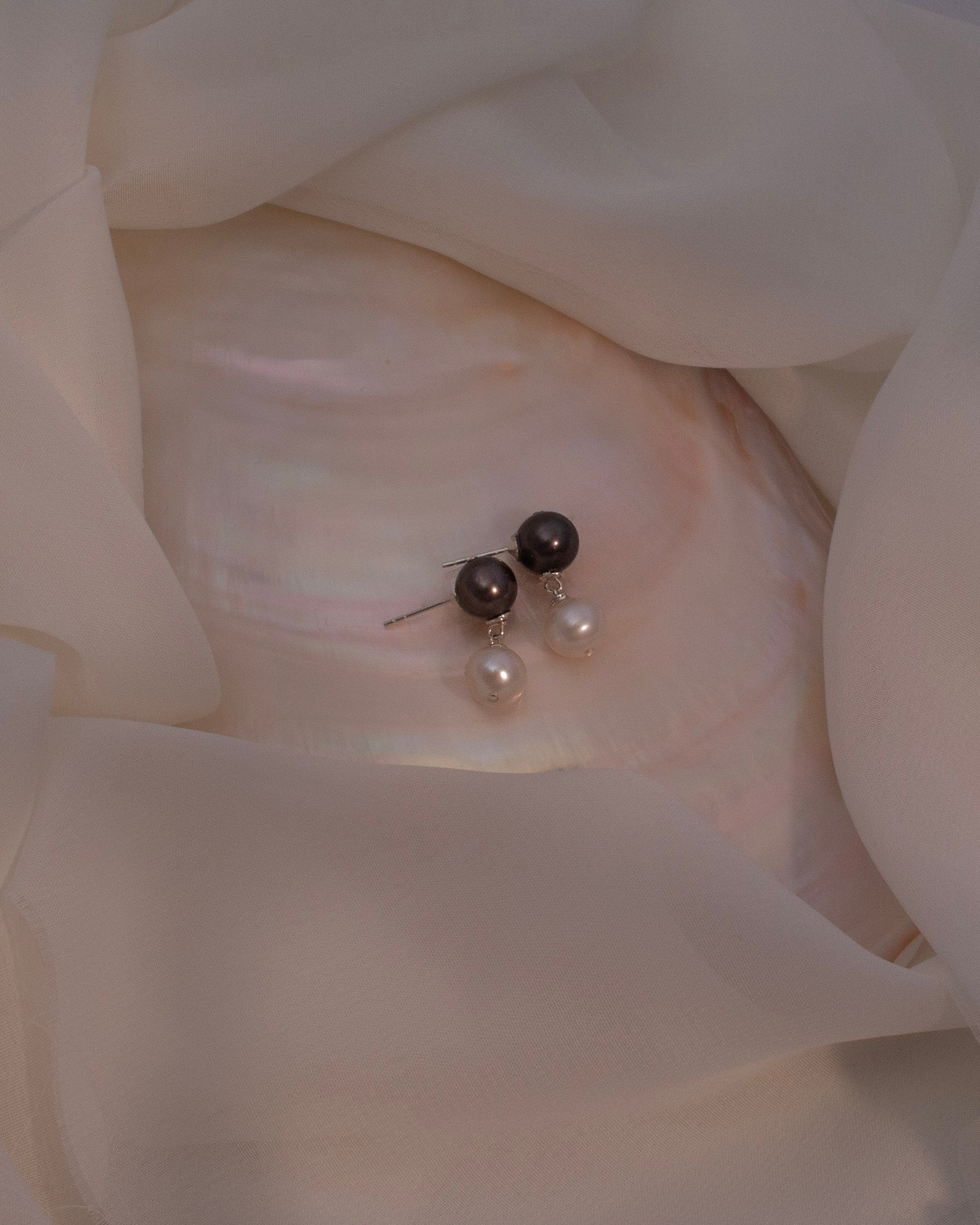 Pair of pearl earrings on a white fabric background