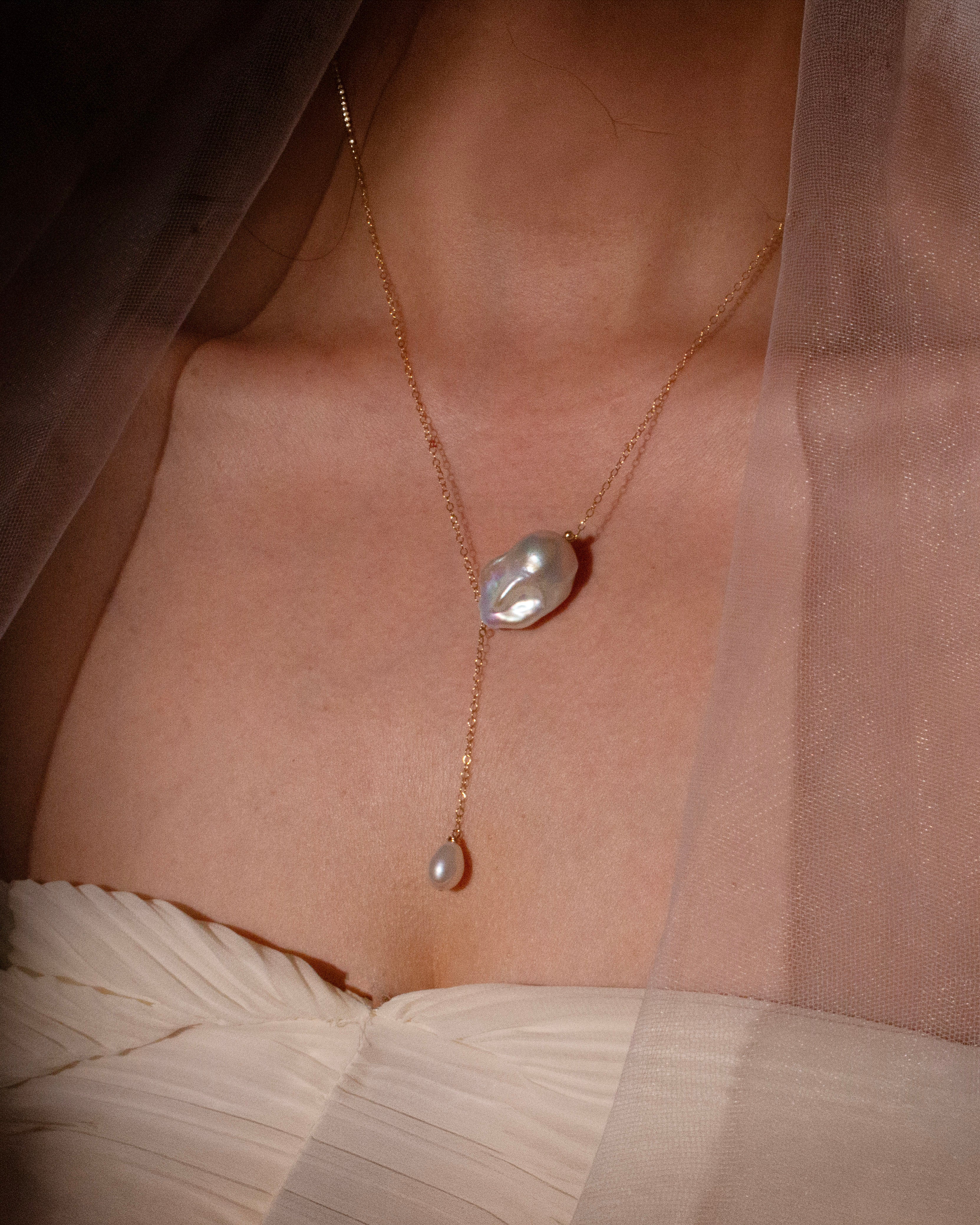 Pearl necklace on a person wearing a sheer white garment