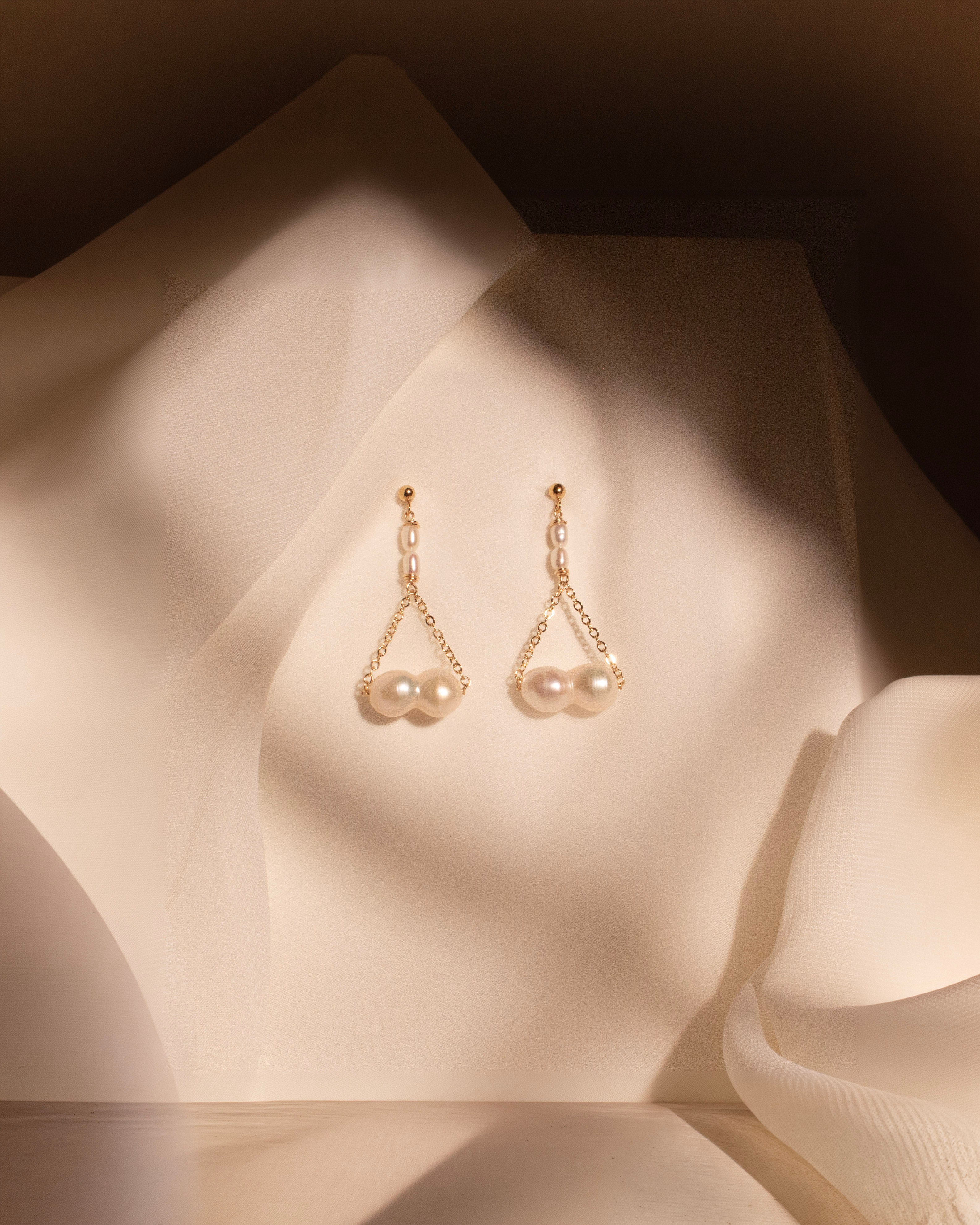 Pair of pearl earrings on a soft fabric background