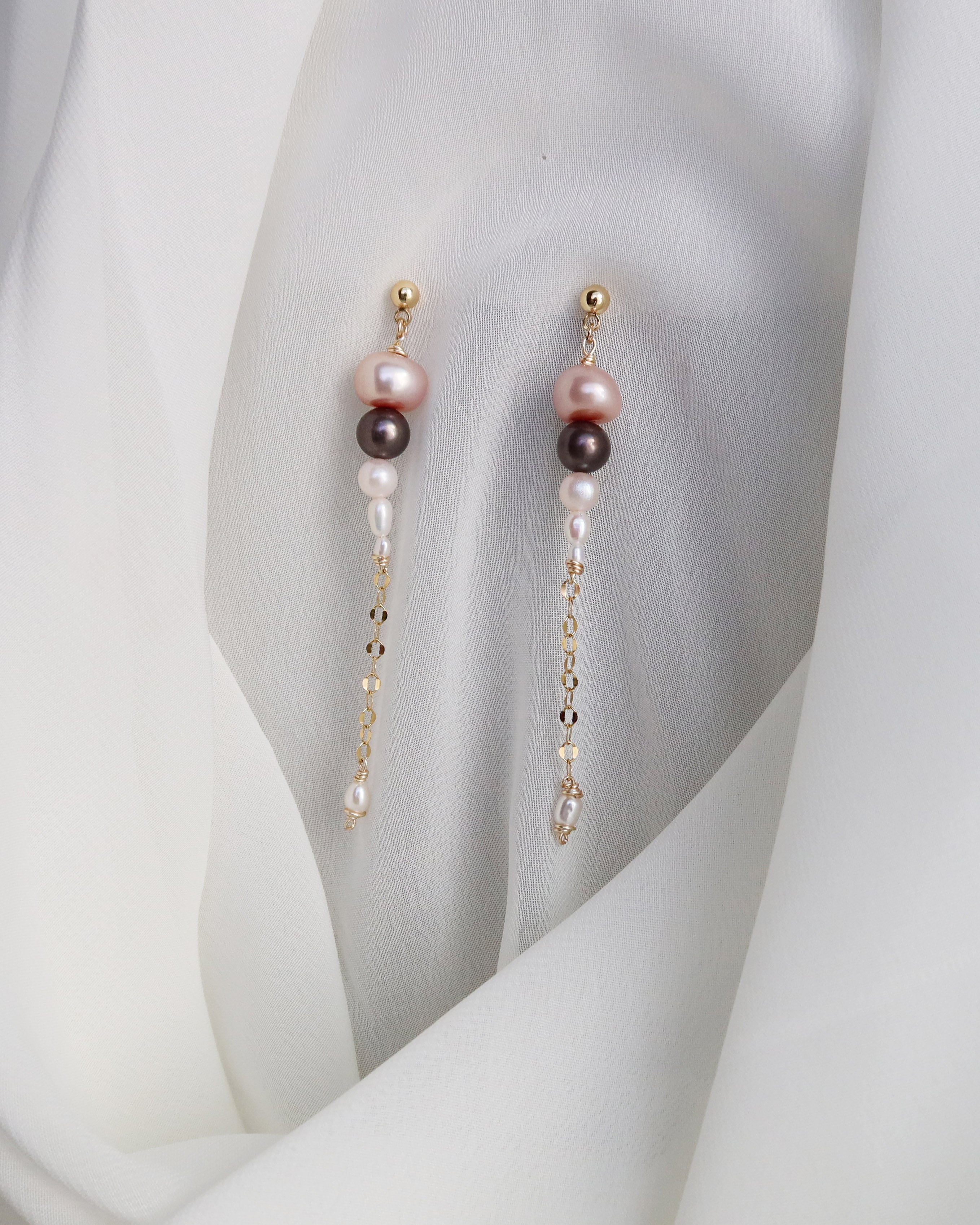 Pearl earrings with gold accents on a white fabric background
