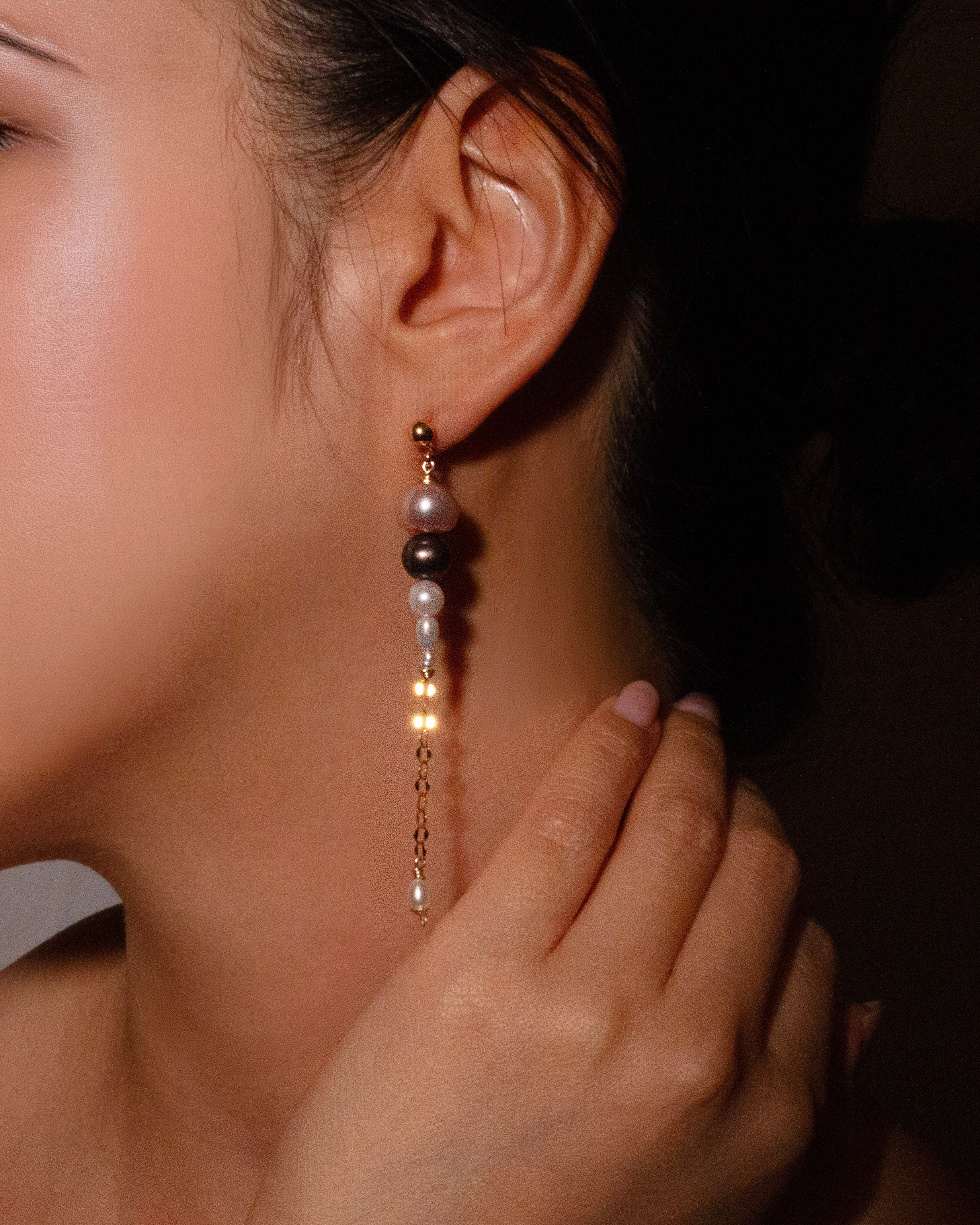 Pearl earring worn by a person with a dark background