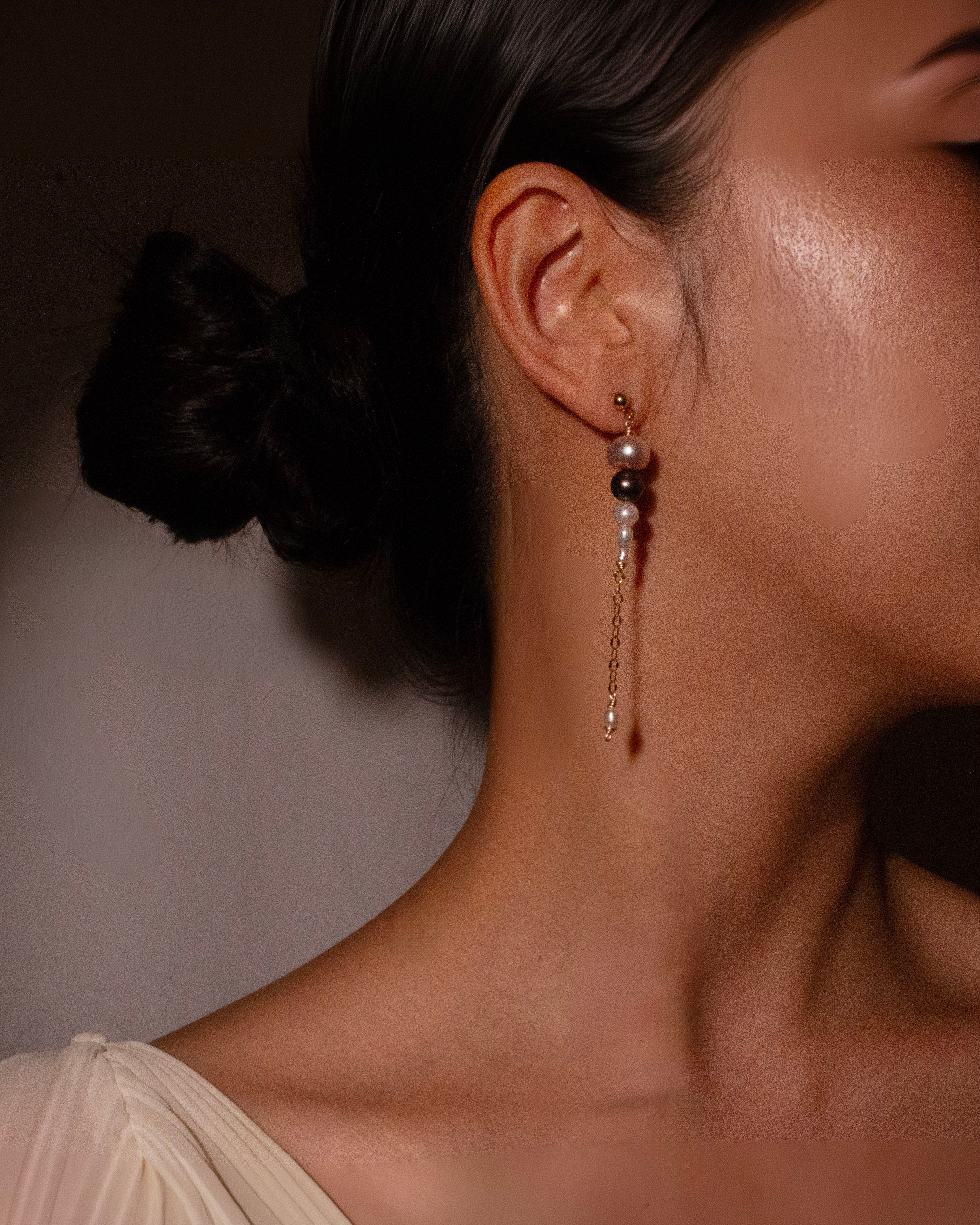 Close-up of an earring on a person's ear with a neutral background