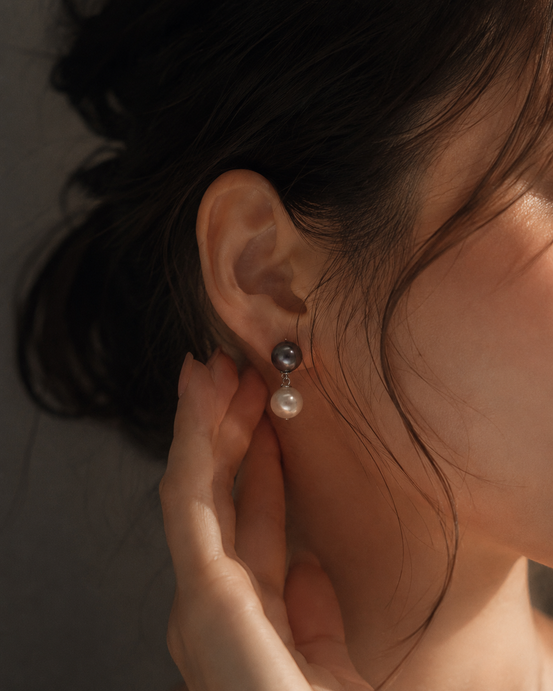 Close-up of a person wearing pearl earrings with a blurred background