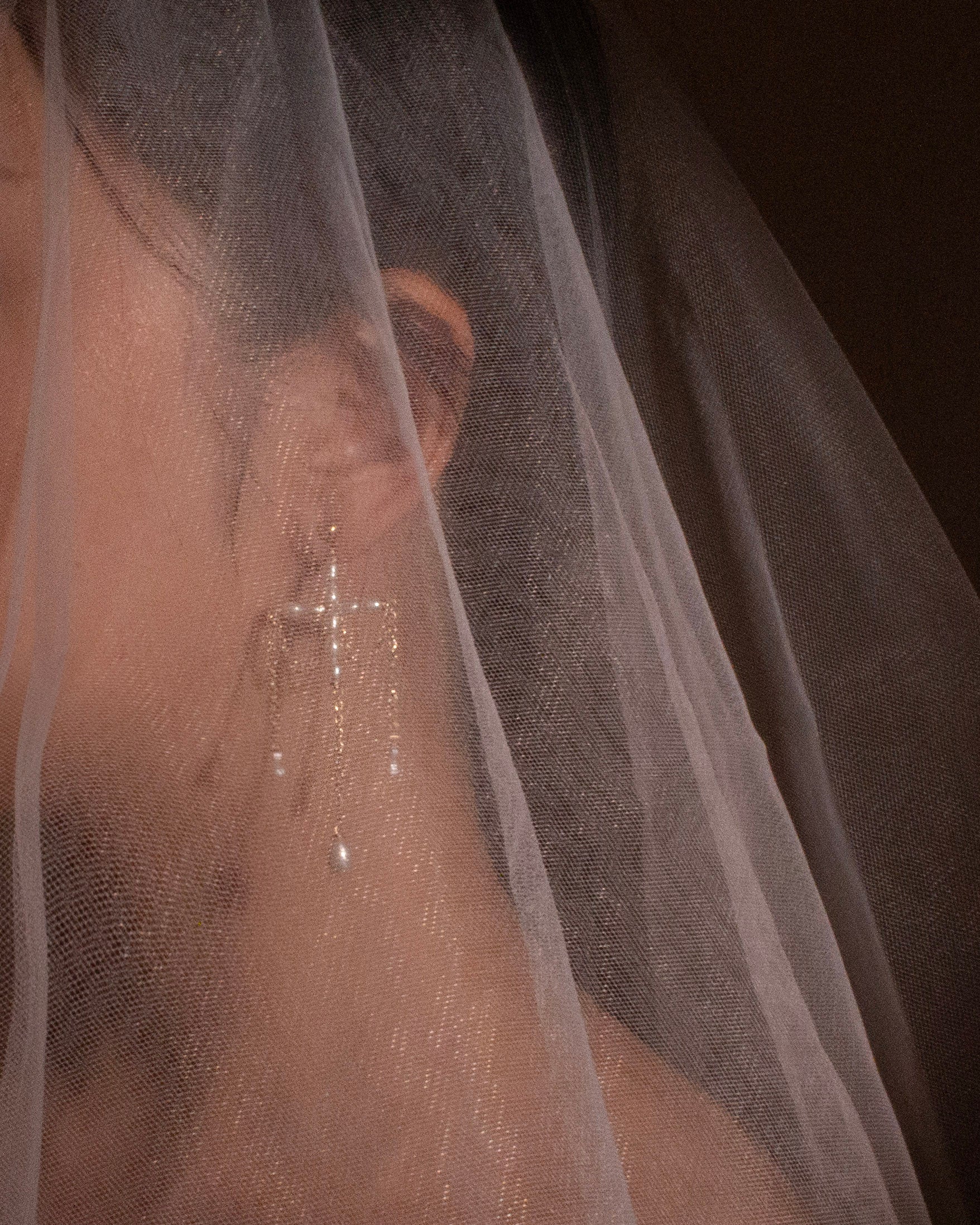 Close-up of a person wearing a sheer white veil with a blurred background
